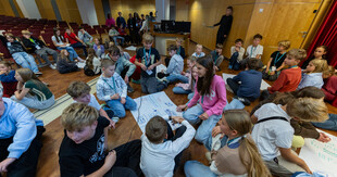 Zdjęcia przedstawiają inaugurację XXXV edycji Ekonomicznego Uniwersytetu Dziecięcego w Katowicach, w której uczestniczyło prawie 150 młodych studentów. Fotografie dokumentują uroczyste rozpoczęcie programu oraz pierwsze zajęcia ekonomiczne dla dzieci.